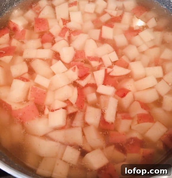 Diced red potatoes covered with water in a large pot on the stove top.