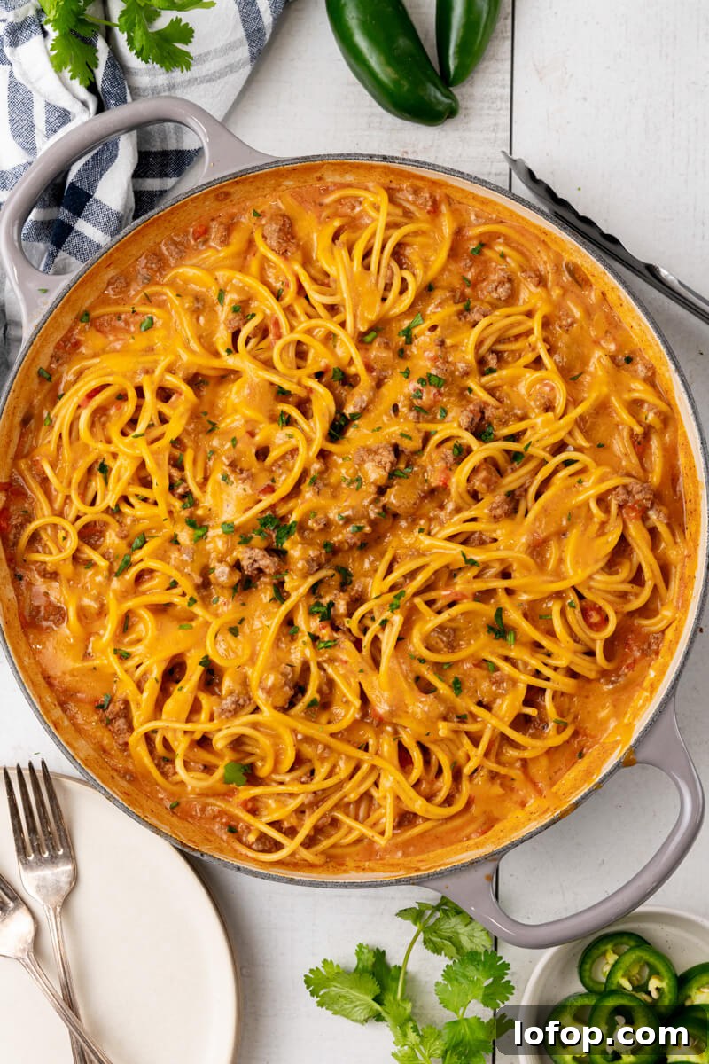 A skillet full of cheesy taco spaghetti and topped with chopped cilantro.