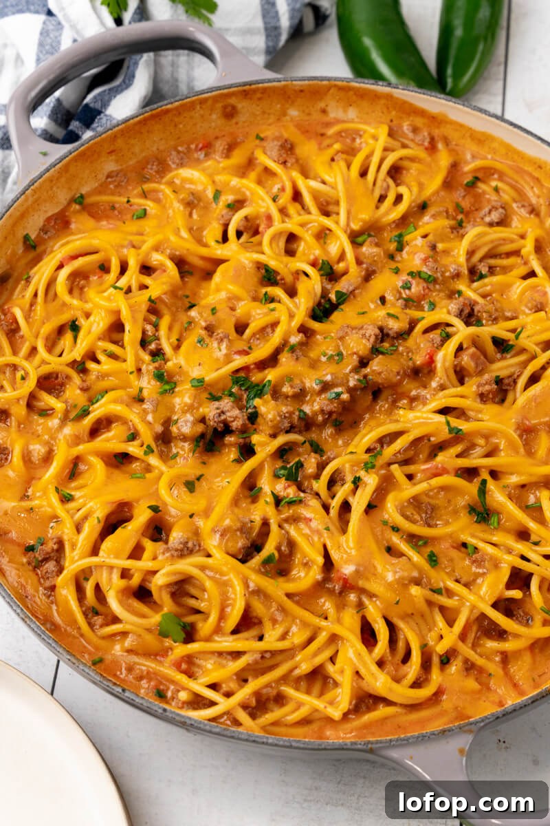 A skillet full of cheesy taco spaghetti and topped with chopped cilantro.