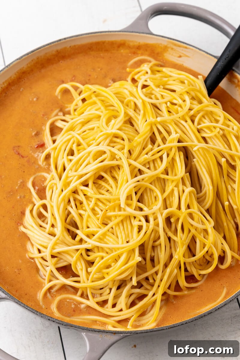 The spaghetti noodles are added o the skillet.