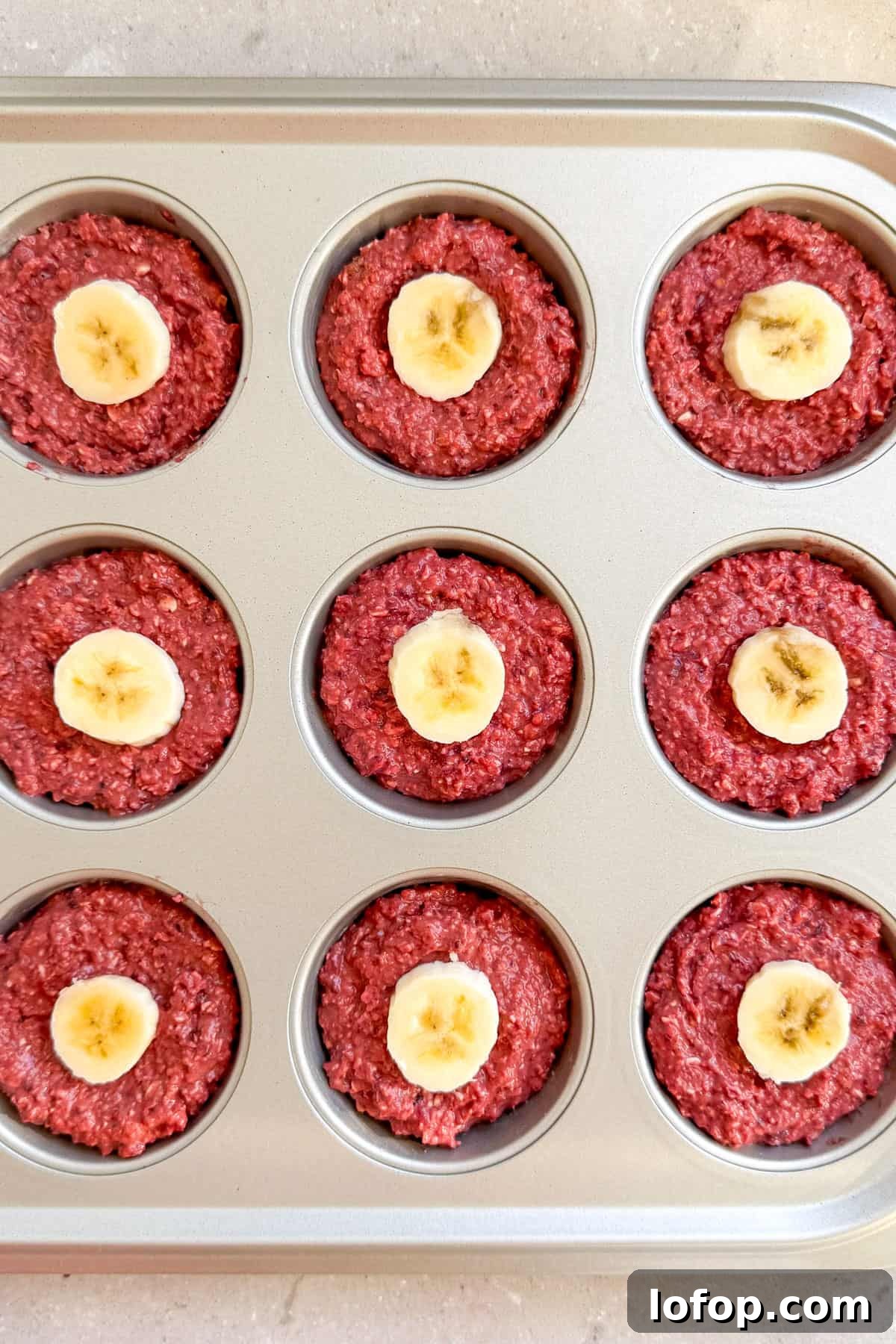 Muffin batter added to muffin panned topped with banana.