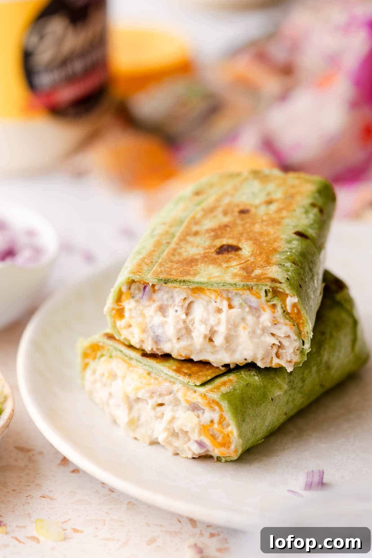 Crispy Tuna Melt Wrap Recipe for Quick Lunches 2 tuna wrap cut in half stacked on white plate.