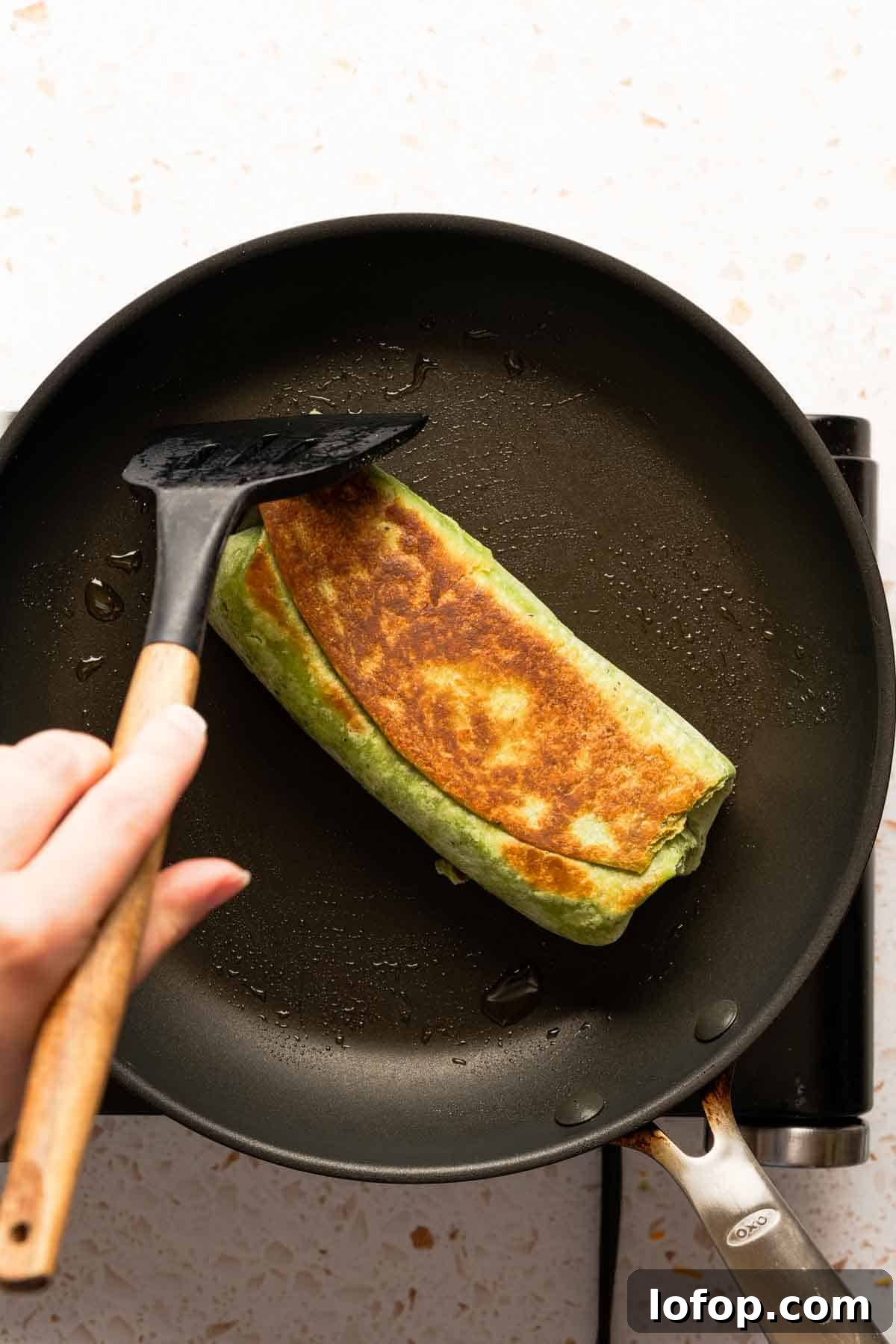 Crispy Tuna Melt Wrap Recipe for Quick Lunches 14 browned tortilla wrap in skillet with spatula.