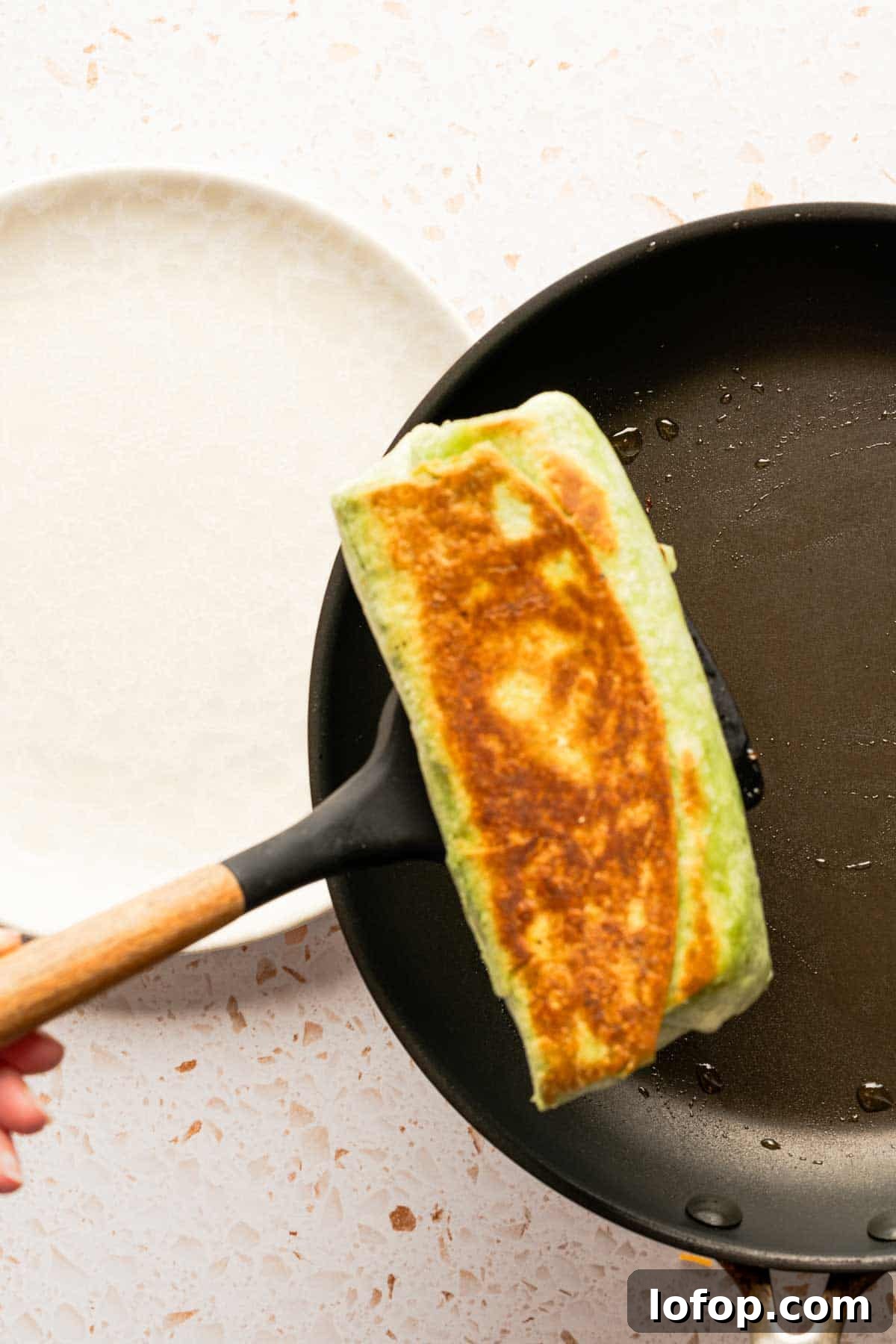 Crispy Tuna Melt Wrap Recipe for Quick Lunches 15 spatula moving browned sandwich wrap from pan to plate.
