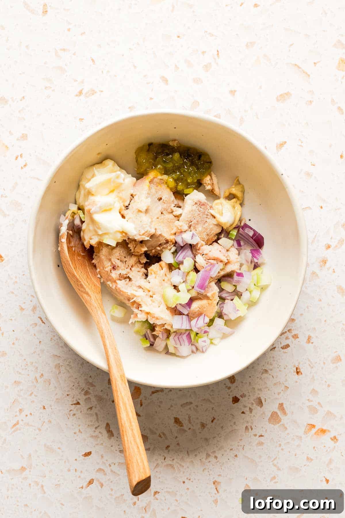 Crispy Tuna Melt Wrap Recipe for Quick Lunches 4 ingredients for tuna salad in bowl with wooden spoon.