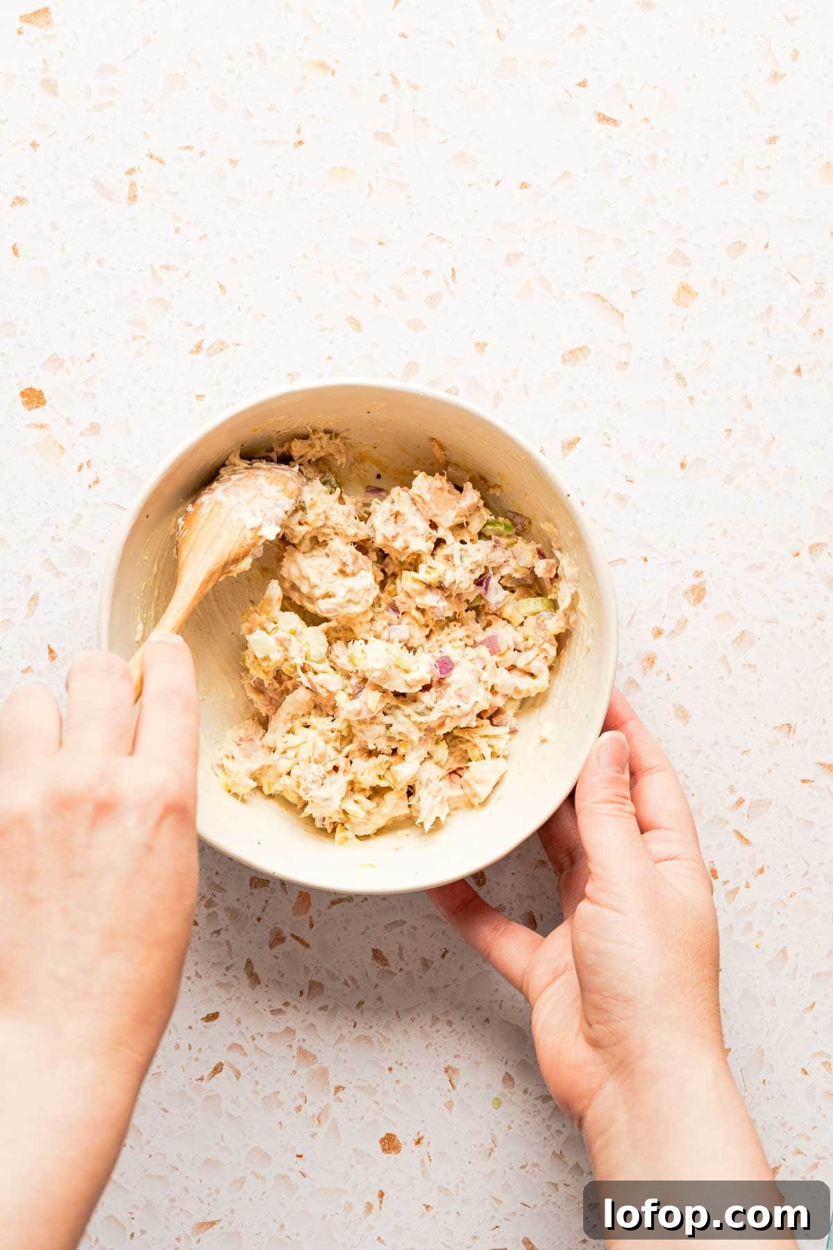 Crispy Tuna Melt Wrap Recipe for Quick Lunches 5 spoon mixing tuna salad in bowl.