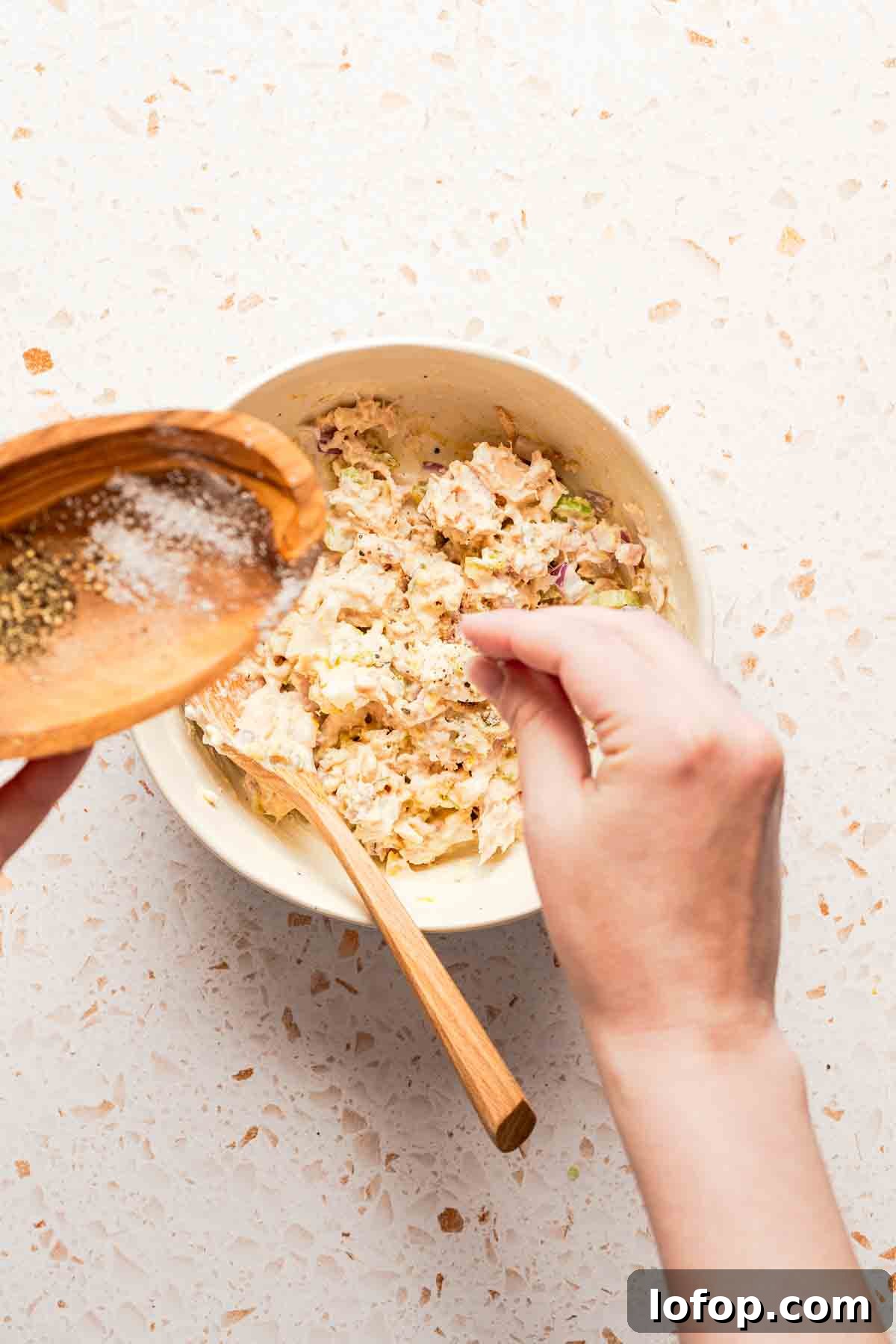 Crispy Tuna Melt Wrap Recipe for Quick Lunches 6 hand sprinkling salt into bowl of tuna salad.