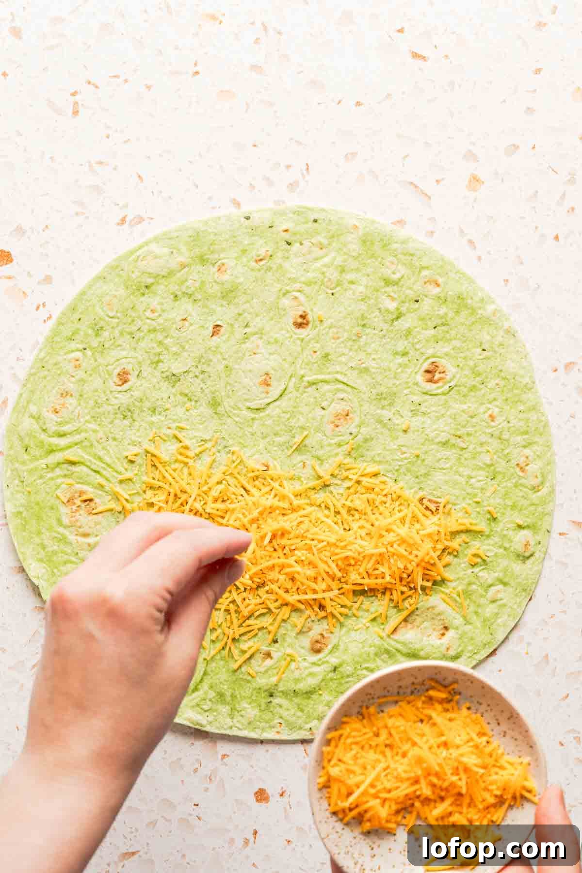 Crispy Tuna Melt Wrap Recipe for Quick Lunches 7 shredded cheese being sprinkled on half of tortilla.