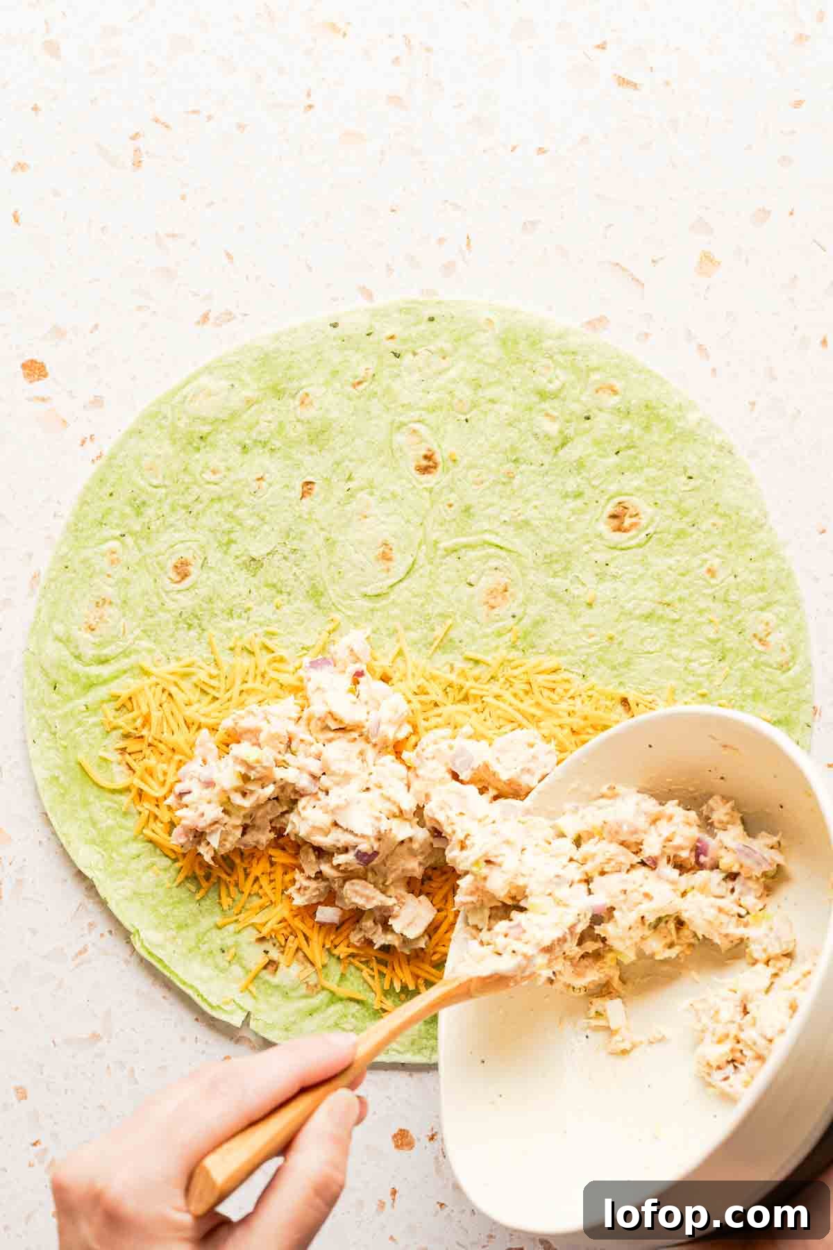 Crispy Tuna Melt Wrap Recipe for Quick Lunches 8 tuna salad being placed on tortilla with cheese.