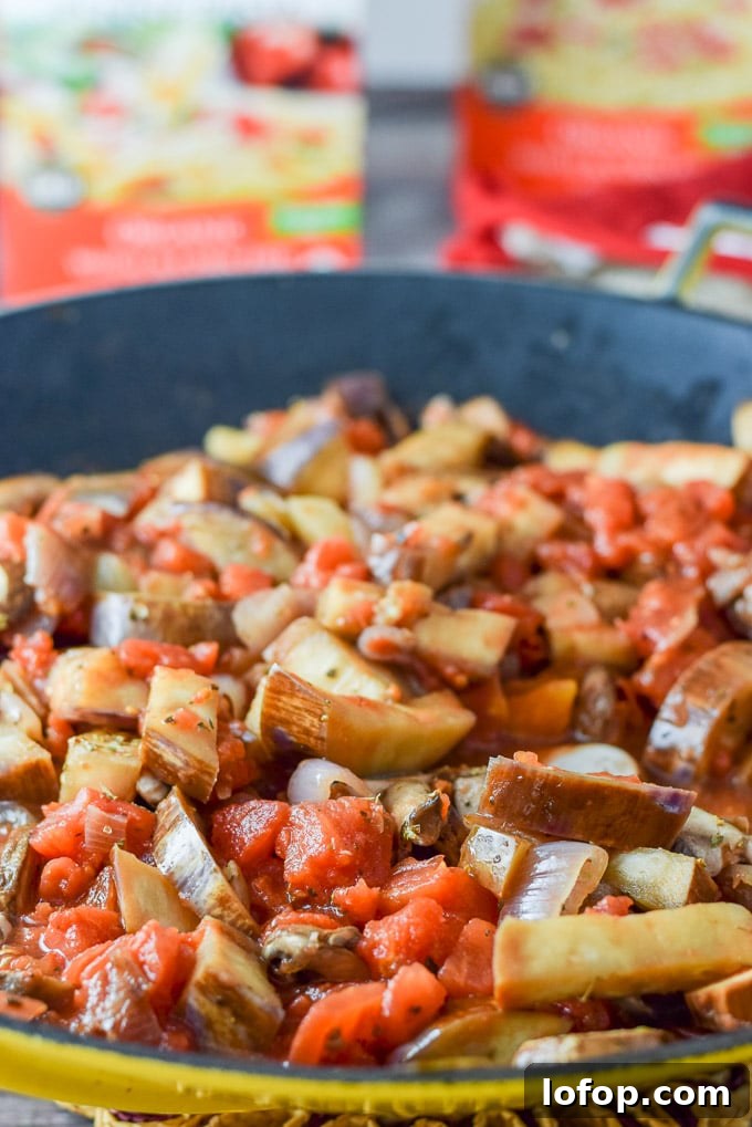 Mushrooms and diced tomatoes added to the shallots and eggplant in the wok