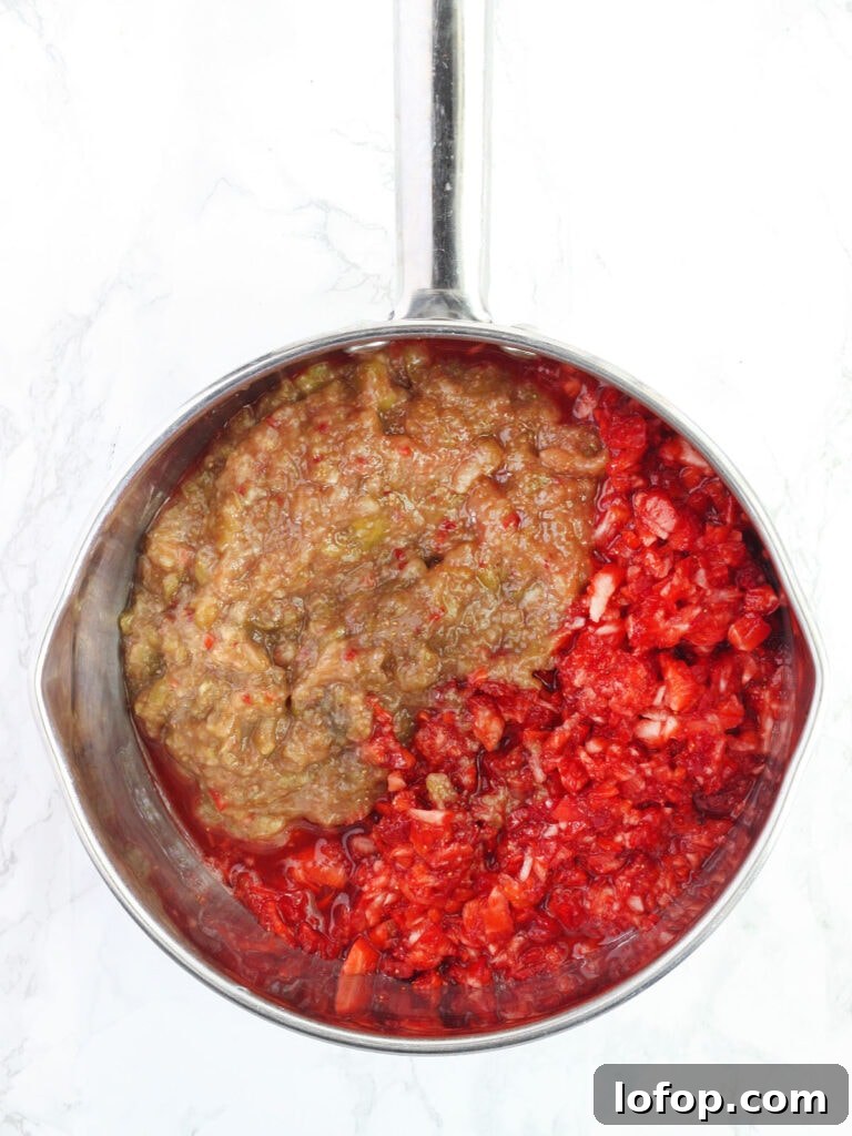 Chopped strawberries and figs unmixed in a stainless steel saucepan.