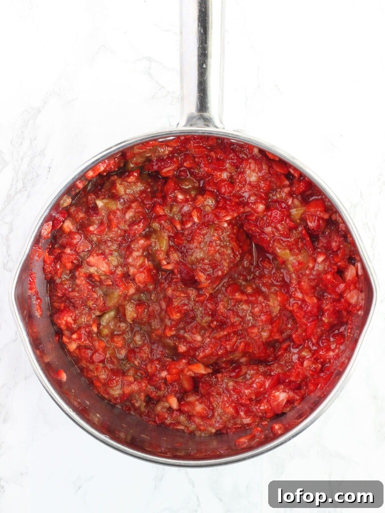 Mashed strawberries and figs mixed together in a stainless steel saucepan.