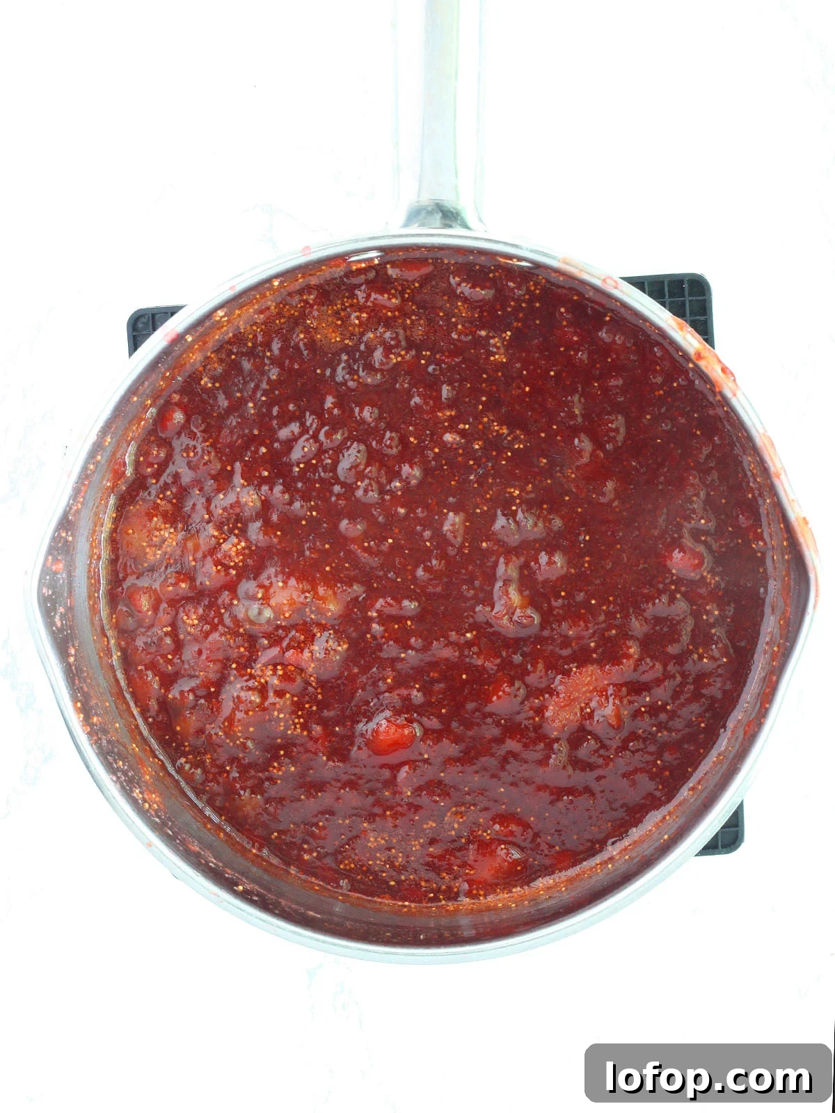 Finished strawberry fig preserves in a stainless steel saucepan.