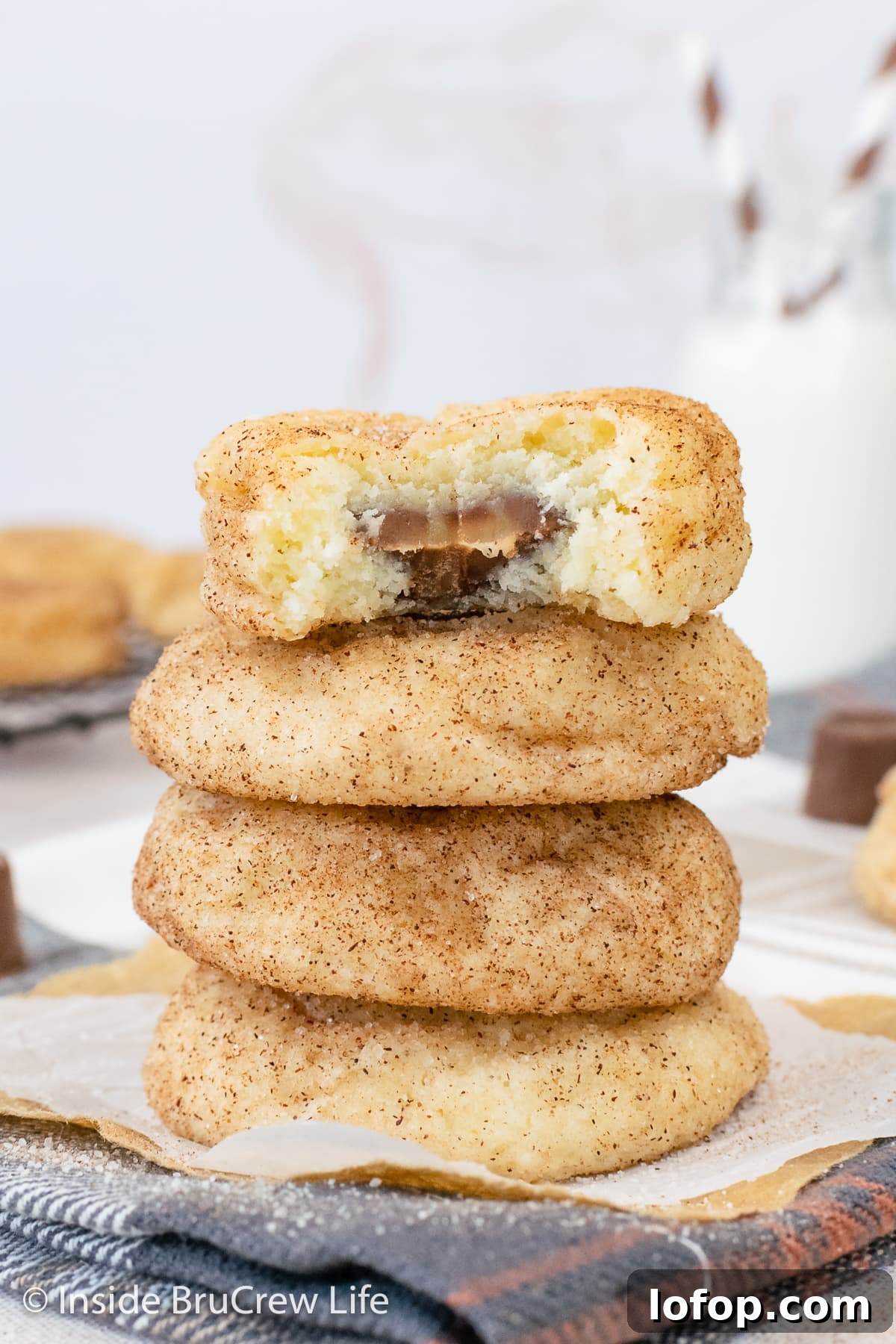 A stack of cinnamon sugar cookies stuffed with caramel candies on a towel.