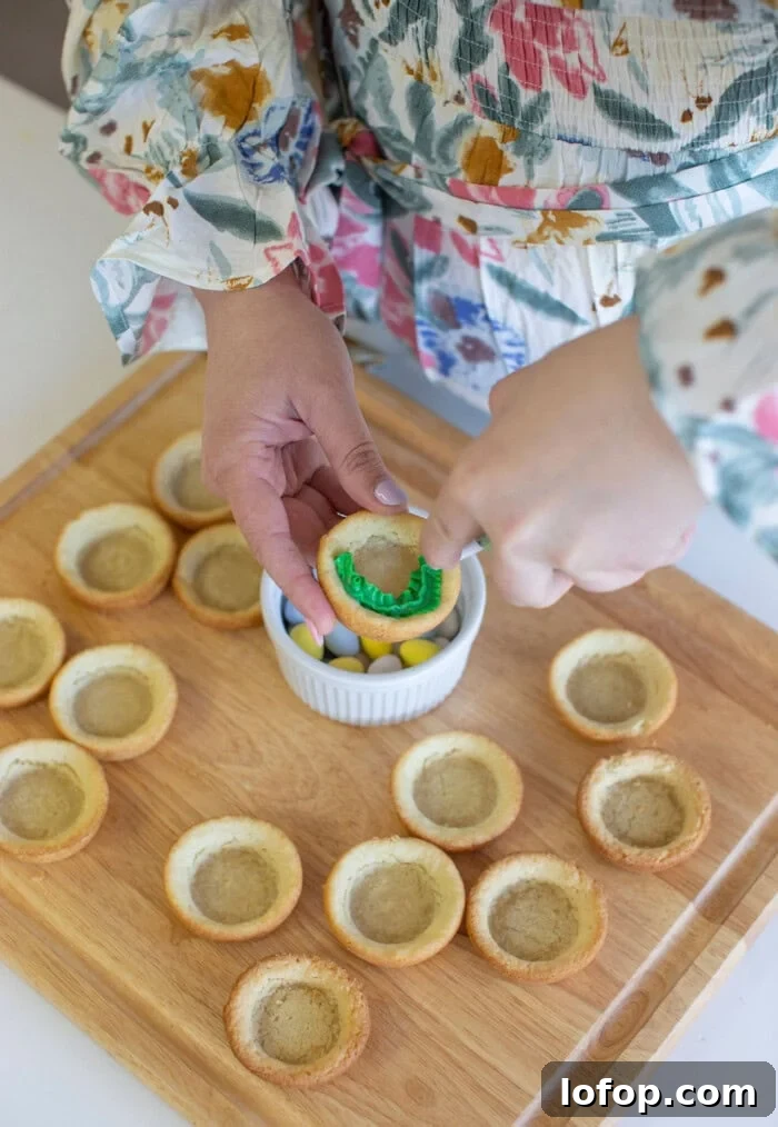 Easter birds nest cookie cups getting green frosting piped into them.