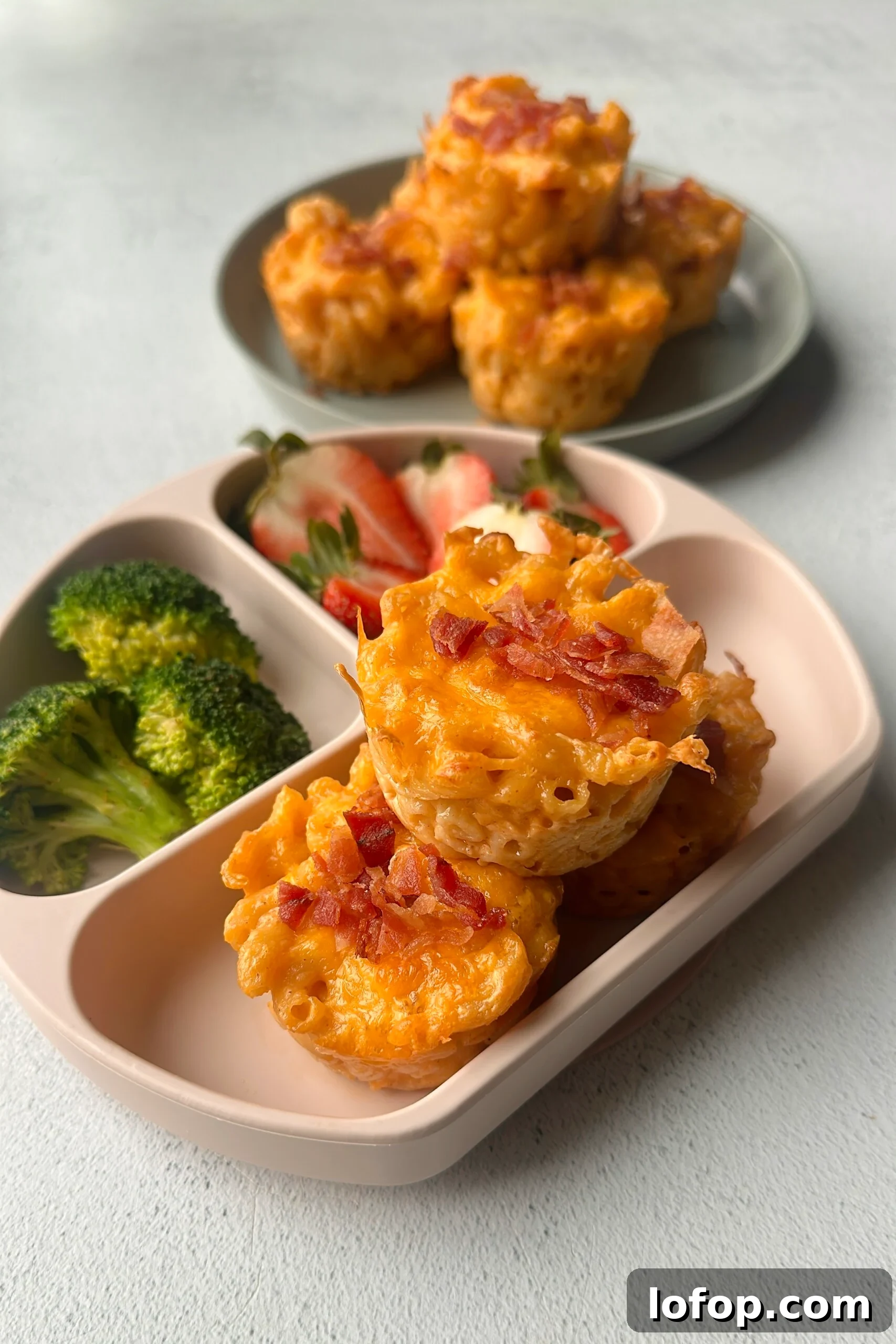 Mac and cheese muffins served with strawberries and broccoli.