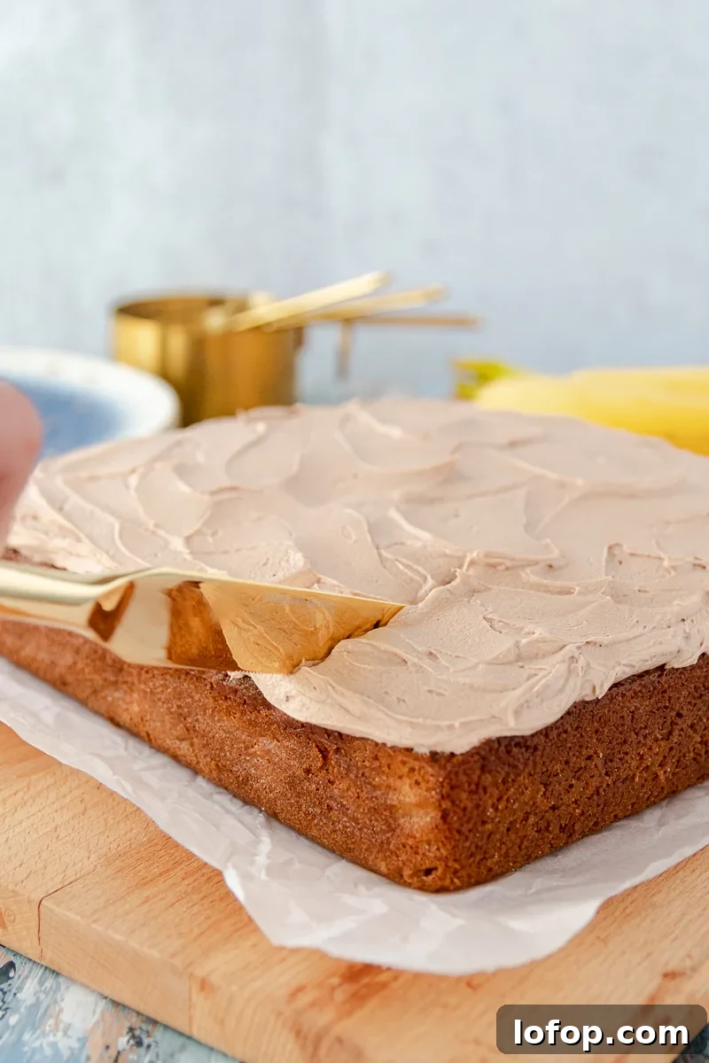Moist Banana Snack Cake with Creamy Nutella Frosting 5 gold knife slicing into the banana snack cake with nutella buttercream frosting