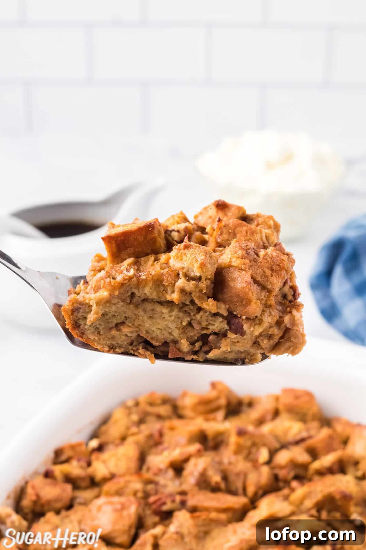 Creamy Pumpkin Bread Pudding with Spiced Caramel Sauce 9 Spatula holding a slice of Pumpkin Bread Pudding over a dish of baked bread pudding.