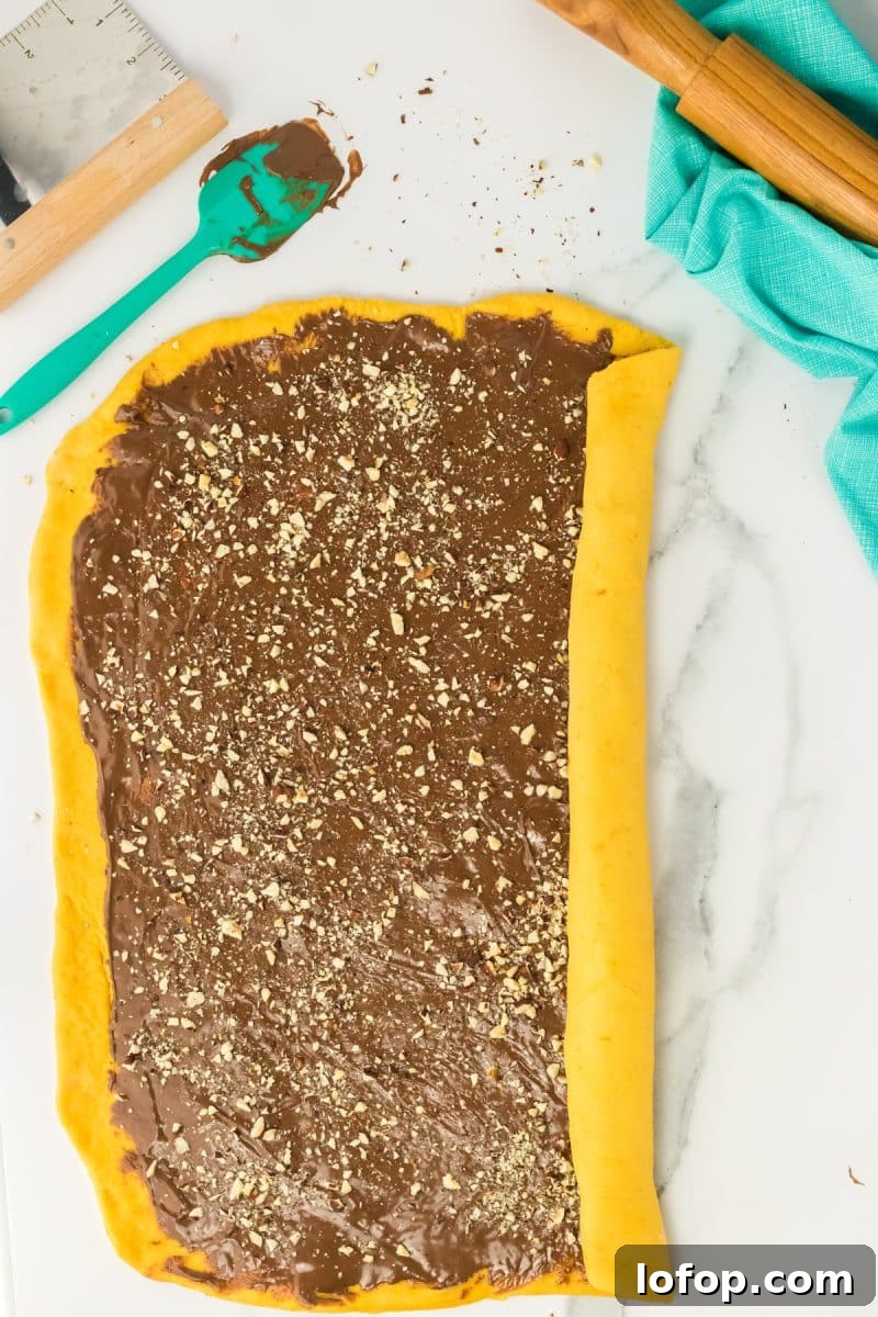 Chocolate nutella and chopped hazelnut filling rolled into a long log of pumpkin yeast bread dough - Hostess At Heart