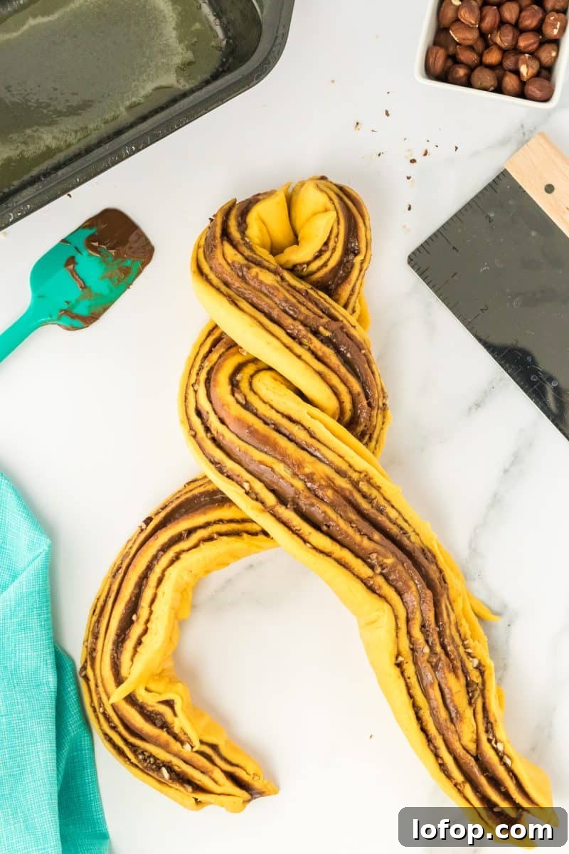 Rolled pumpkin babka bread that's been sliced and is now being twisted with the filled sides up.
