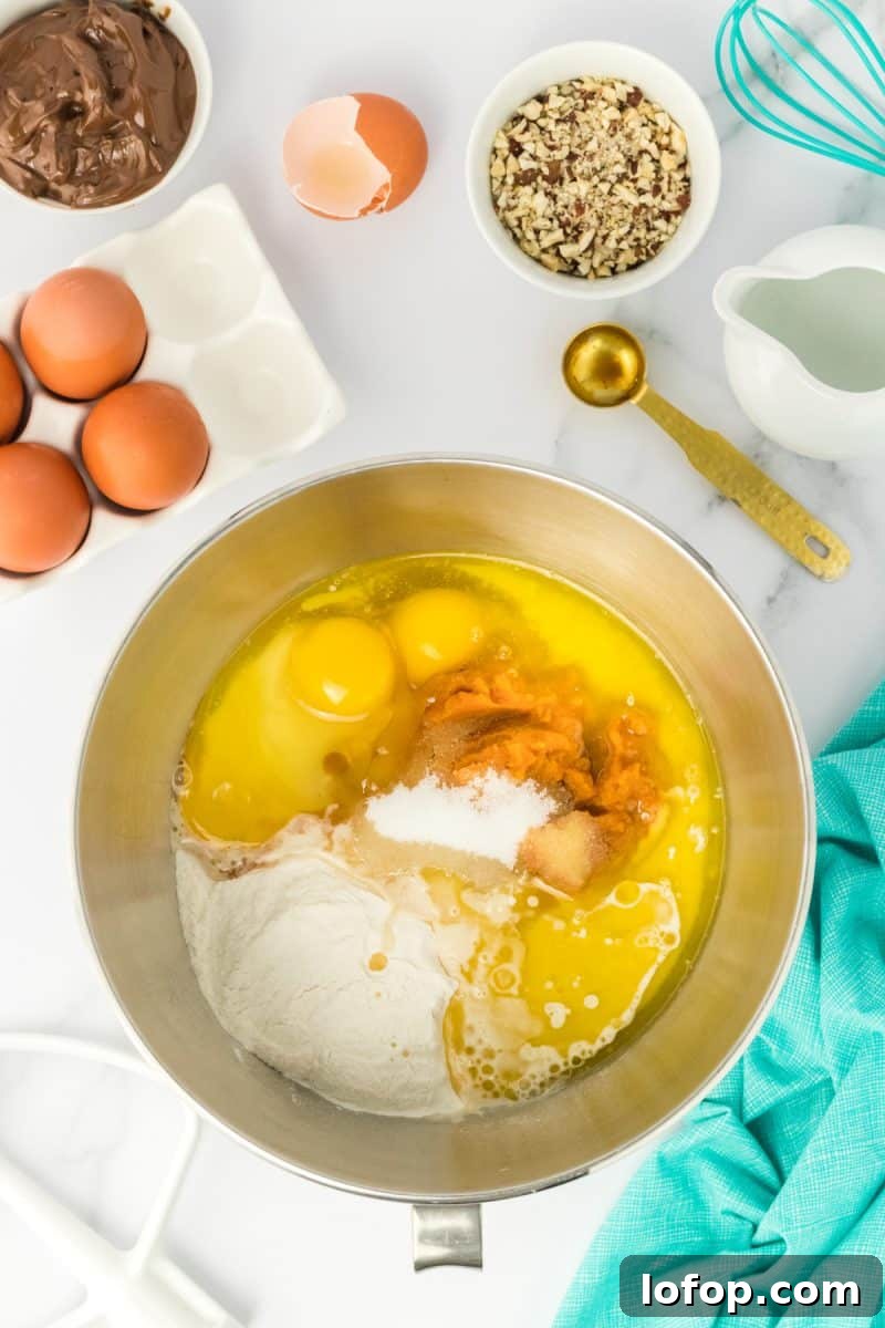 Top down view of a mixer bowl filled with pumpkin babka bread ingredients including flour, pumpkin, butter, salt, and sugar - Hostess At Heart
