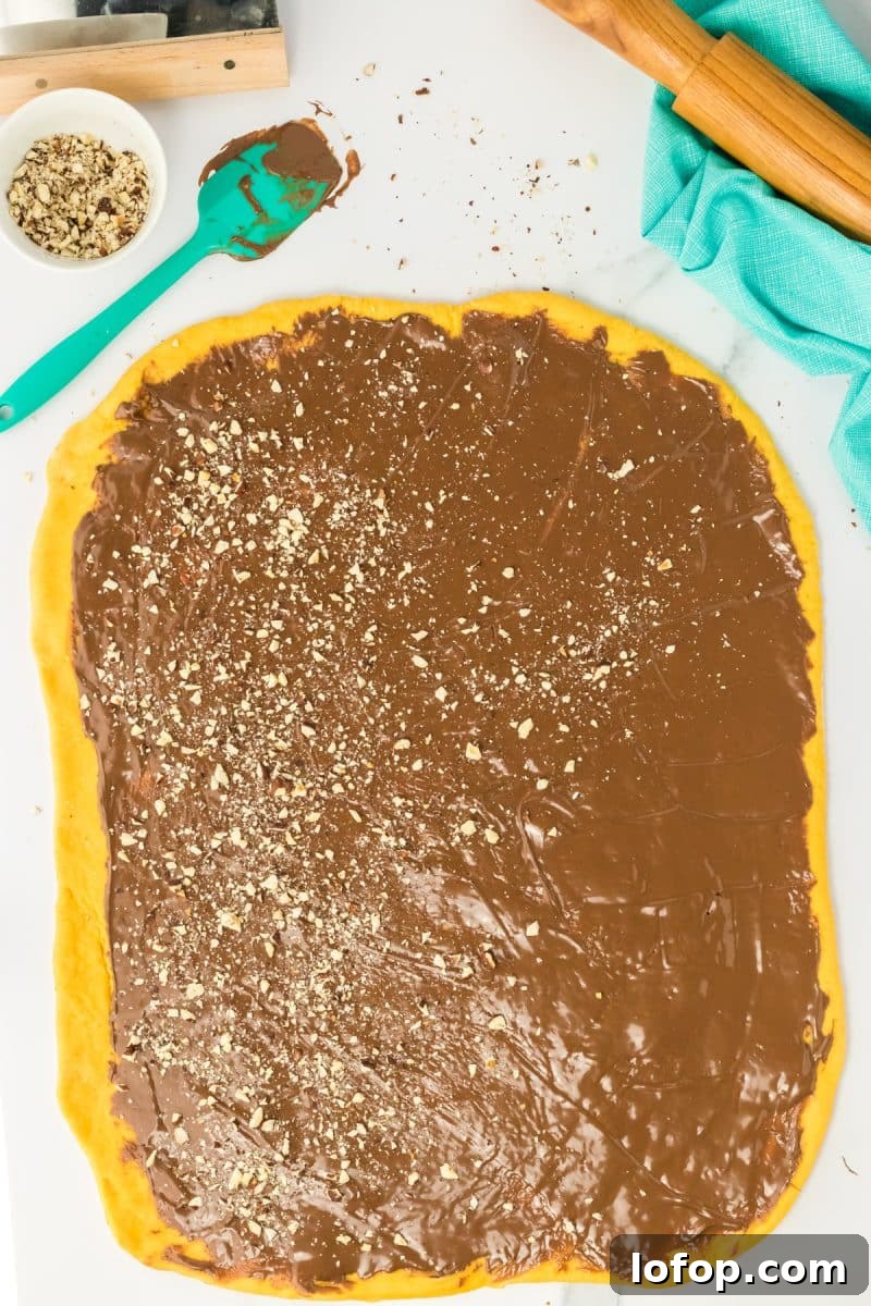 Rolled pumpkin yeast bread dough topped with chocolate nutella hazelnut filling - Hostess At Heart