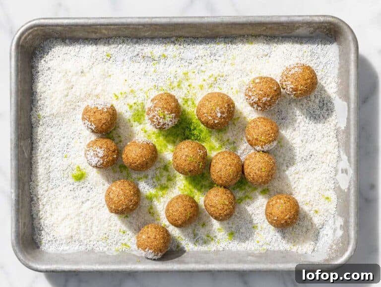 Step 2 energy balls ready to roll in shredded coconut on a baking tray