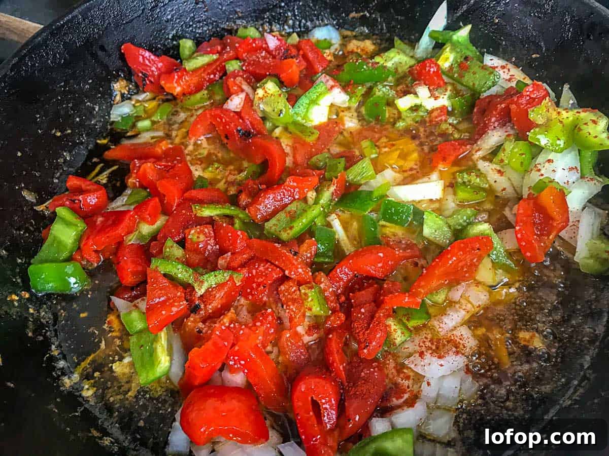 Onions, red peppers and green bell peppers in a cast iron skillet