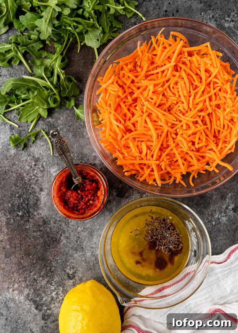 overhead: bowls of harissa carrots and vinaigrette for carrot salad
