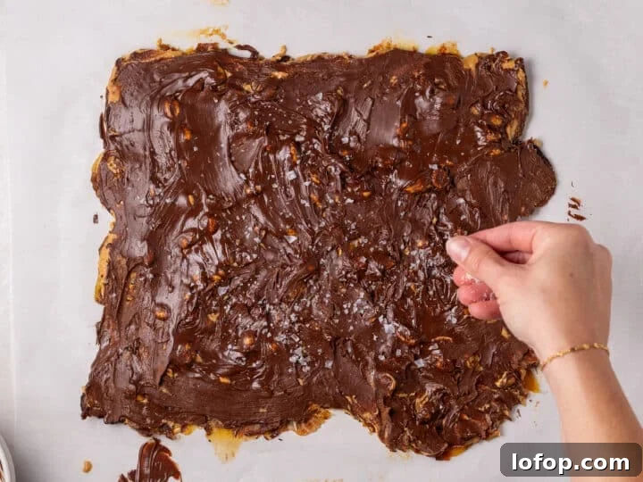 Flaky sea salt being sprinkled over the melted chocolate layer