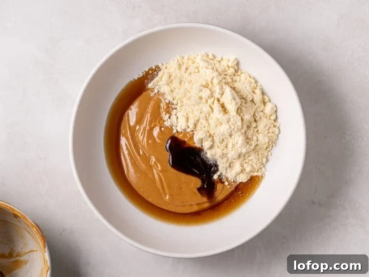 Peanut butter mixture in a bowl with vanilla protein powder, maple syrup, and vanilla extract