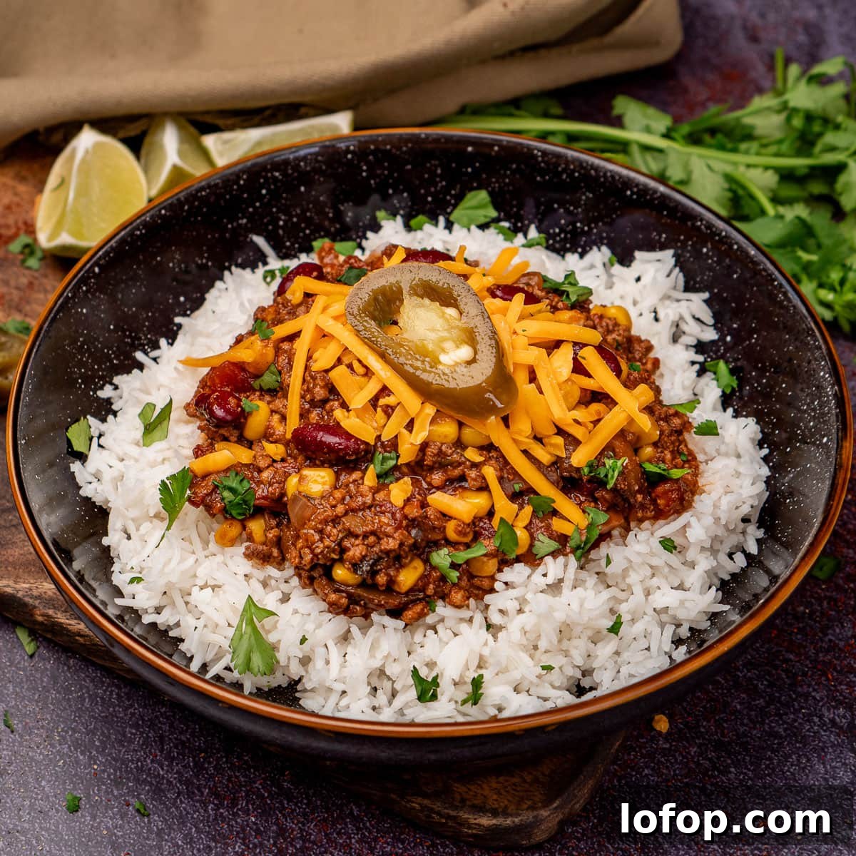 Slow Cooker Chilli Con Carne served with white rice and red leicester cheese and a jalapeno on top