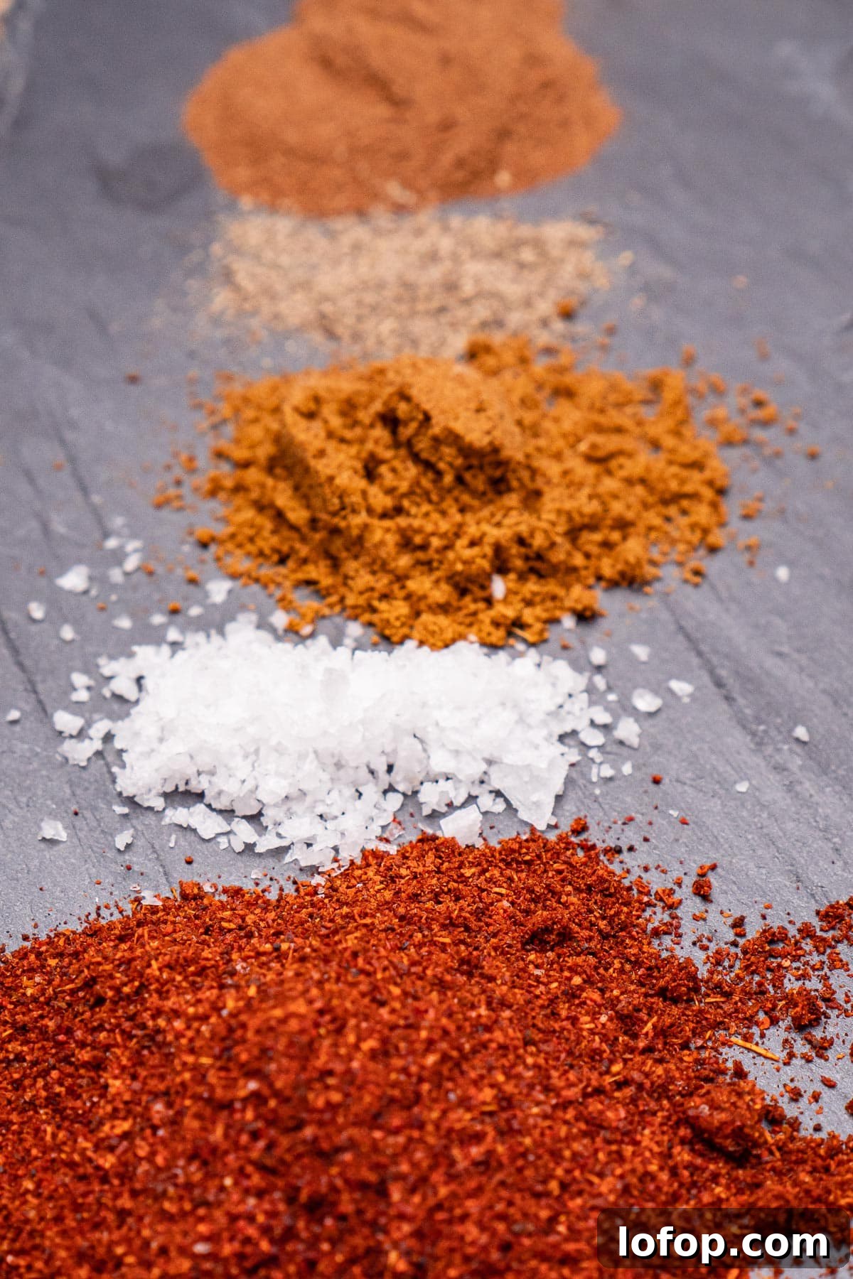 Hot chilli powder, salt, ground cumin, black pepper and ground cinnamon on a piece of slate