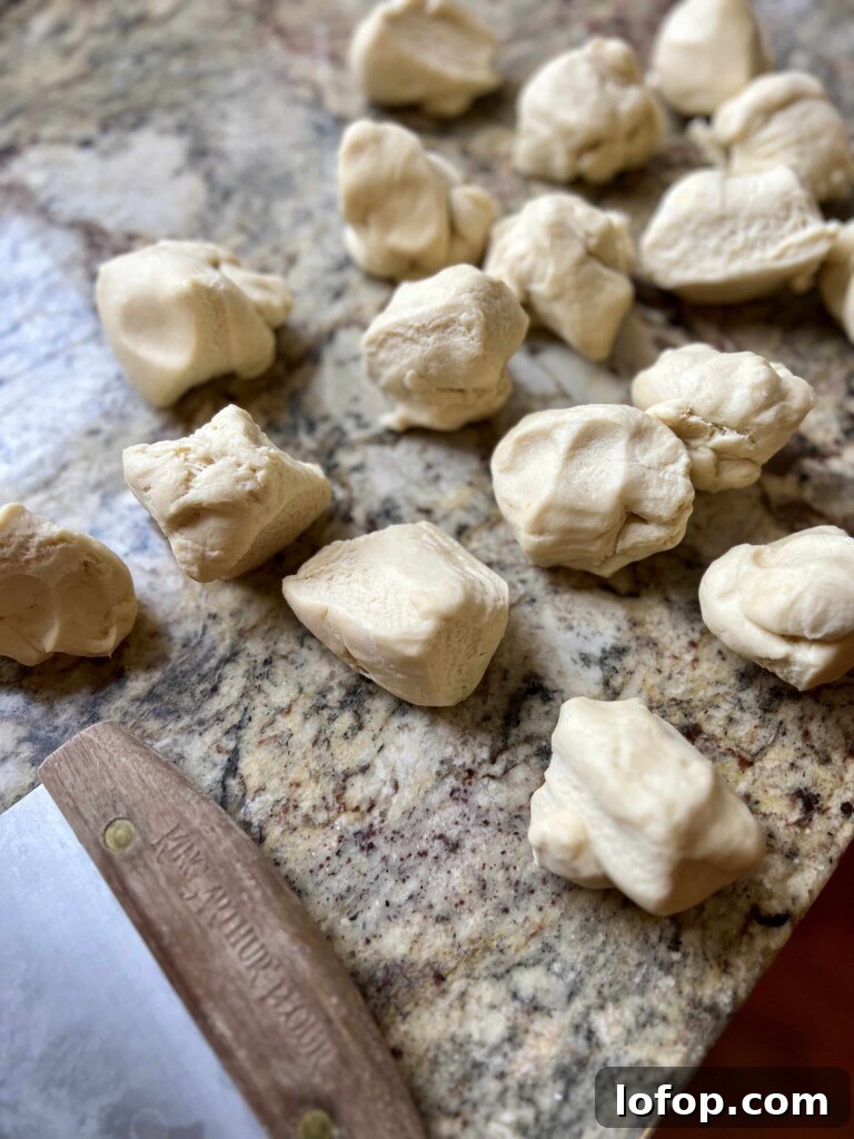 Pieces of sourdough kolache dough divided on a granite countertop with a bench scraper.