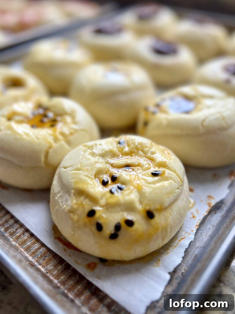 Baked sourdough kolaches topped with passion fruit jam on a sheet pan.