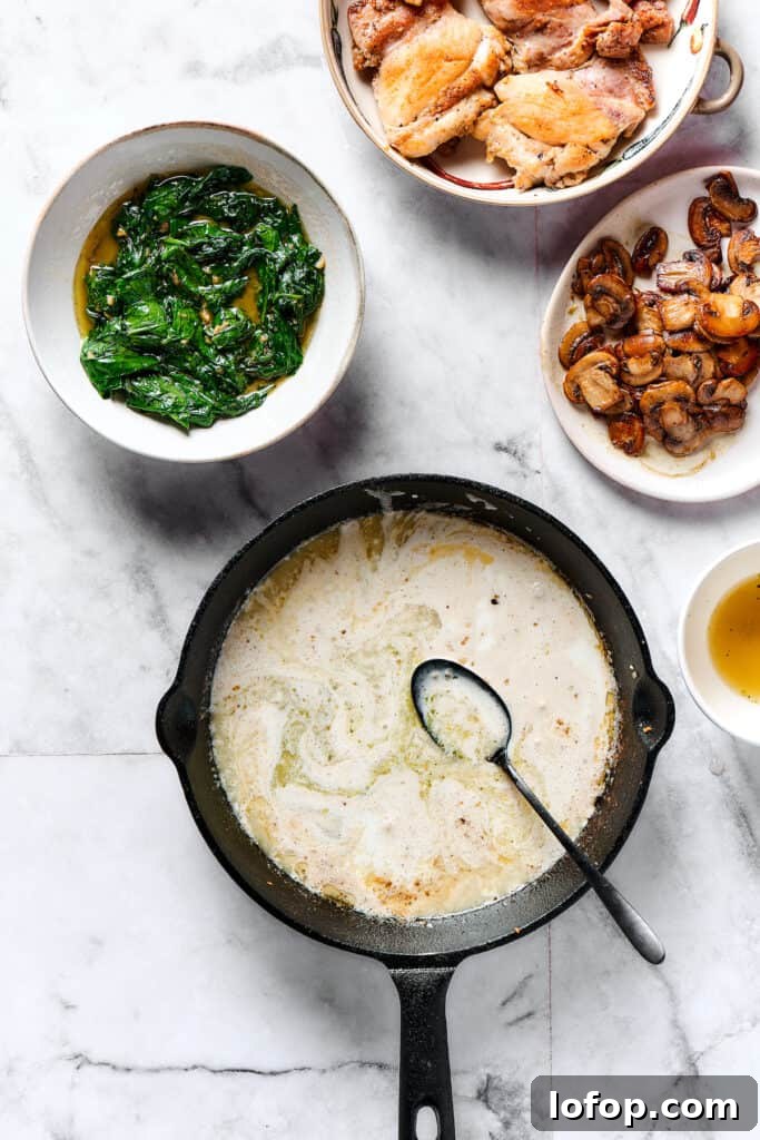 Creamy Chicken and Gnocchi Skillet with Garlic Parmesan Sauce 5 A creamy sauce cooking in a skillet, with plates of spinach, chicken, and mushrooms arranged nearby.