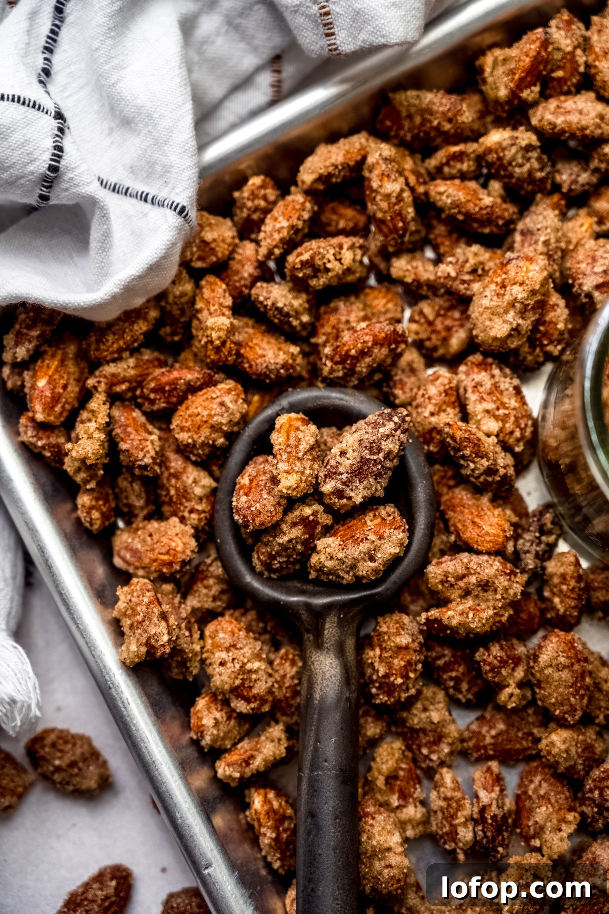 Cinnamon Sugar Candied Almonds Recipe | Crunchy Roasted Almonds 2 Aerial photo of a serving spoon scooping up candied almonds from a baking sheet.