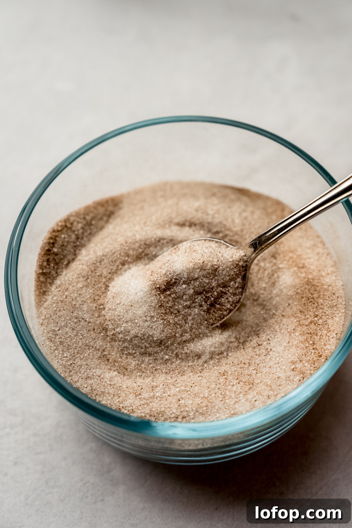 Cinnamon Sugar Candied Almonds Recipe | Crunchy Roasted Almonds 4 A small glass bowl of cinnamon sugar with a spoon in it.
