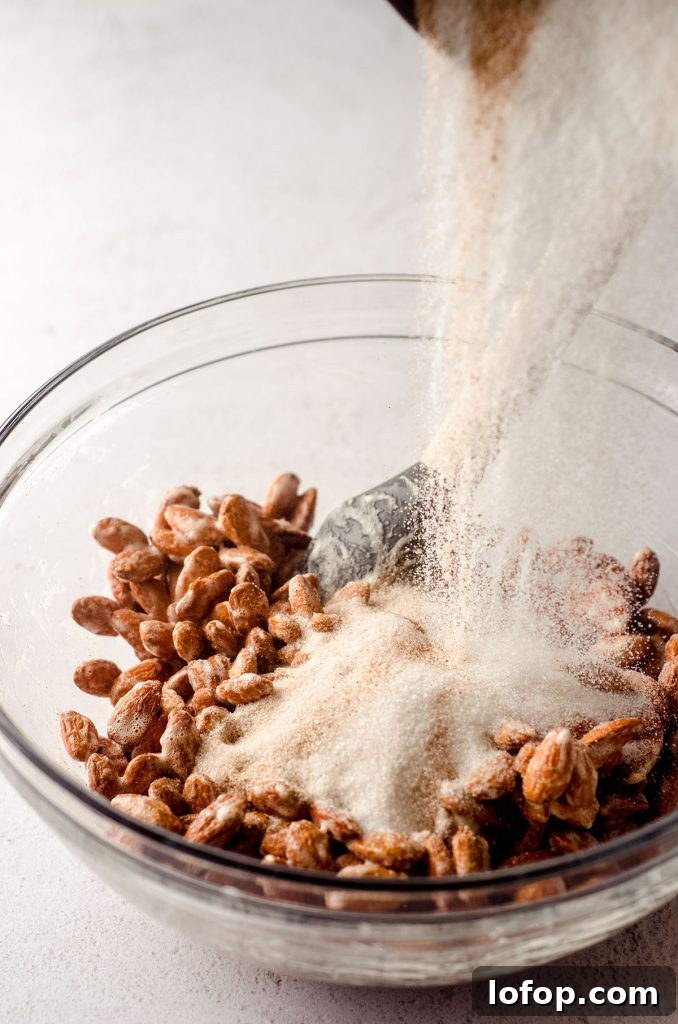 Cinnamon Sugar Candied Almonds Recipe | Crunchy Roasted Almonds 6 a bowl of almonds coated in vanilla bean paste and frothed egg whites with a bowl of sugar and cinnamon pouring on top to make candied almonds