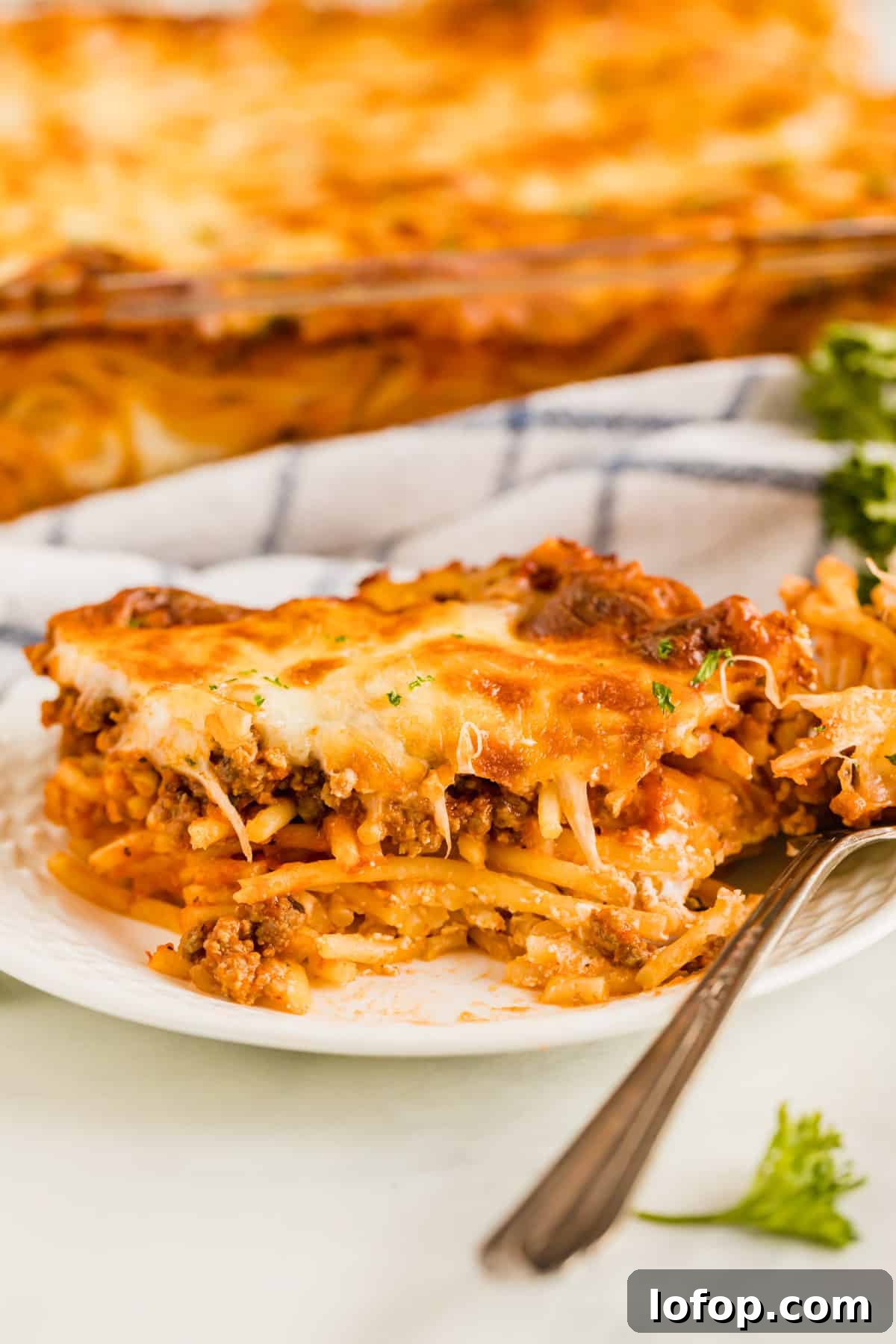 Ultimate Cheesy Baked Spaghetti Recipe for Comfort Dinner 2 A piece of baked spaghetti with a bite taken out of it revealing the pasta inside.
