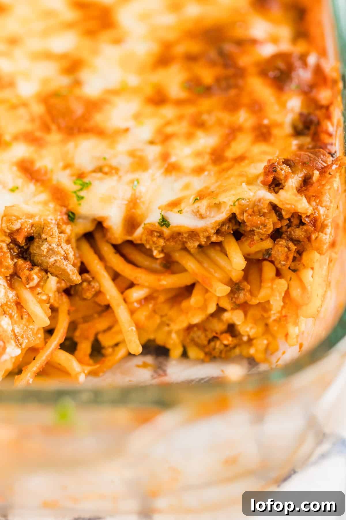 Ultimate Cheesy Baked Spaghetti Recipe for Comfort Dinner 10 A close up image of the baked spaghetti in the pan after a scoop has been removed.