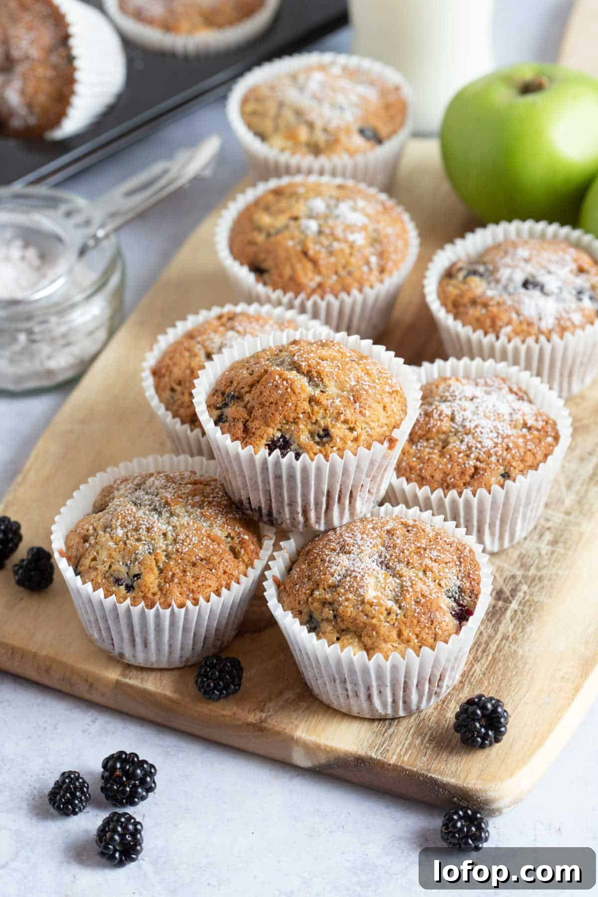 Apple and blackberry muffins on a wooden board.