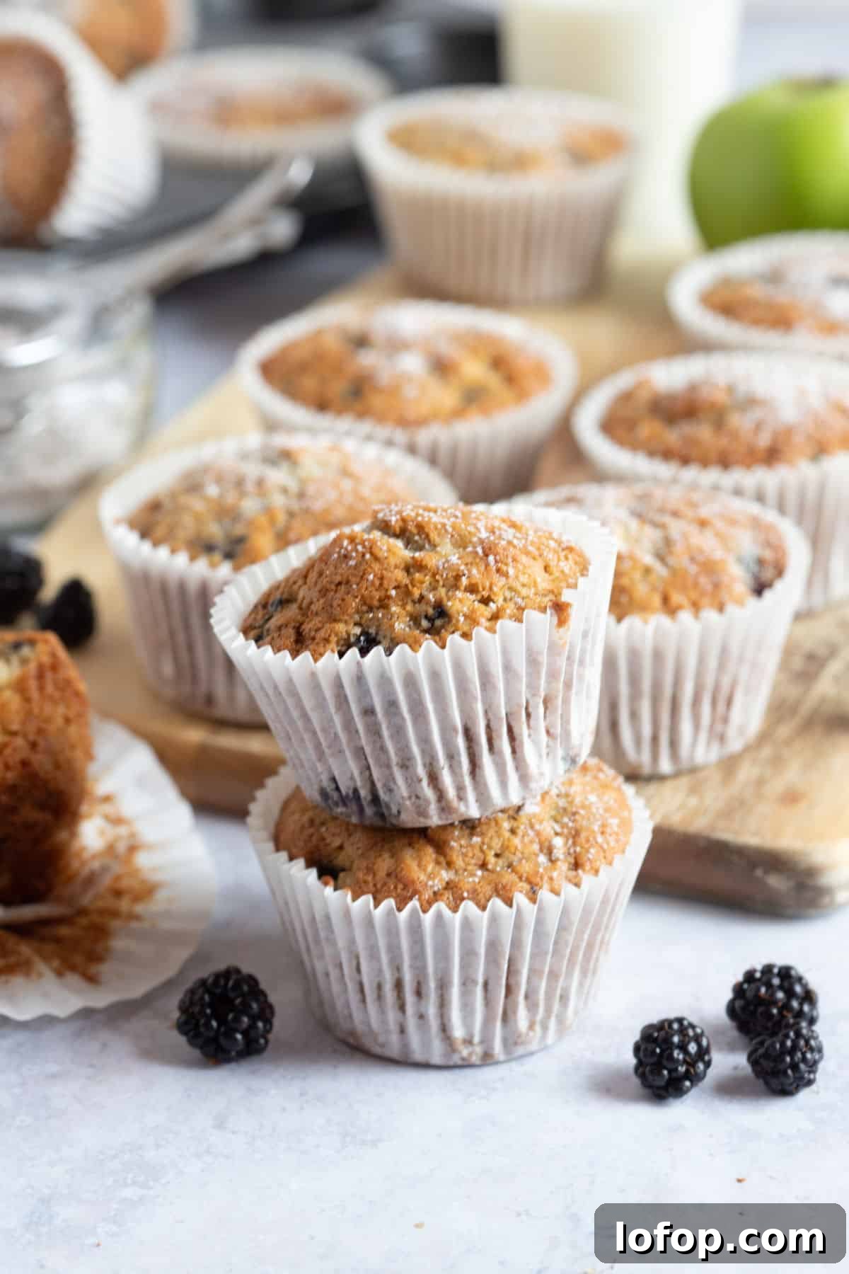 Two apple and blackberry muffins stacked on top of each other.