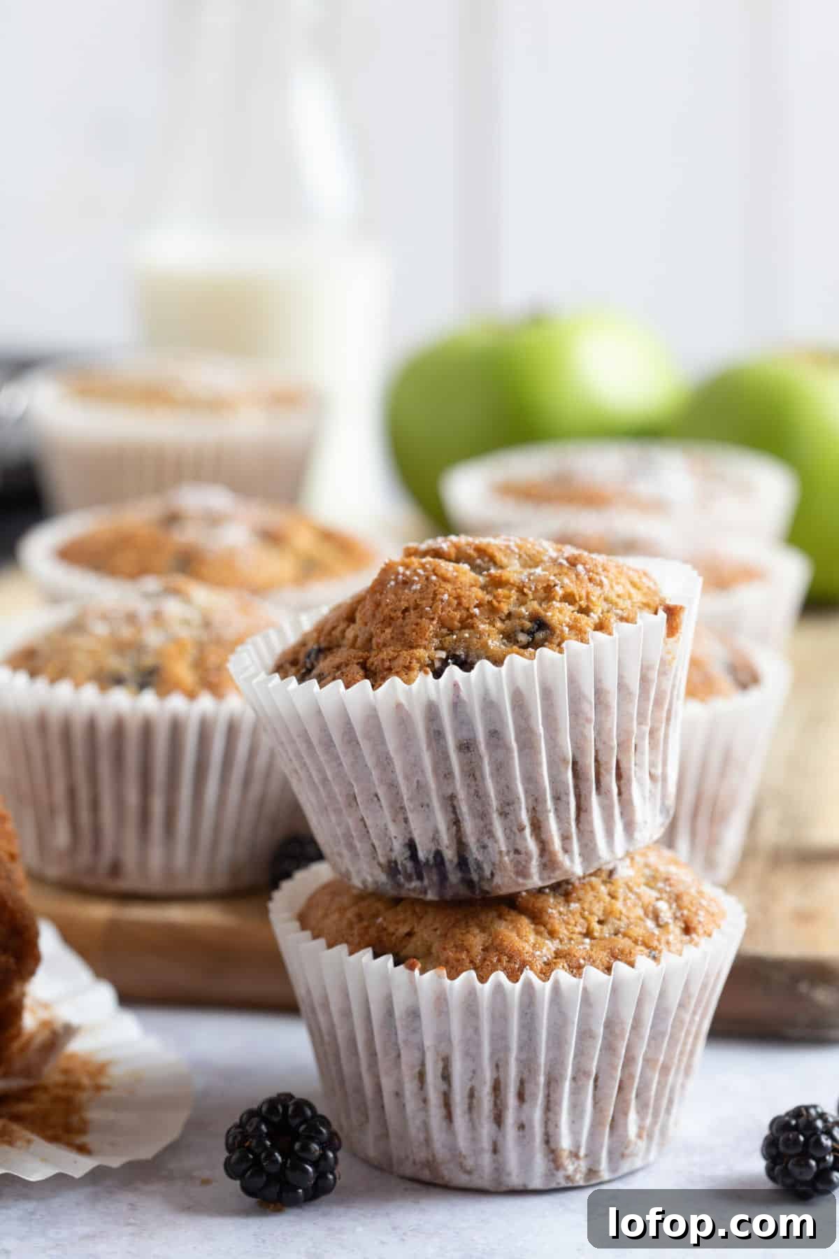 Two apple and blackberry muffins with a glass of milk.