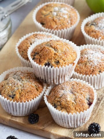 Apple and blackberry muffins on a wooden board.