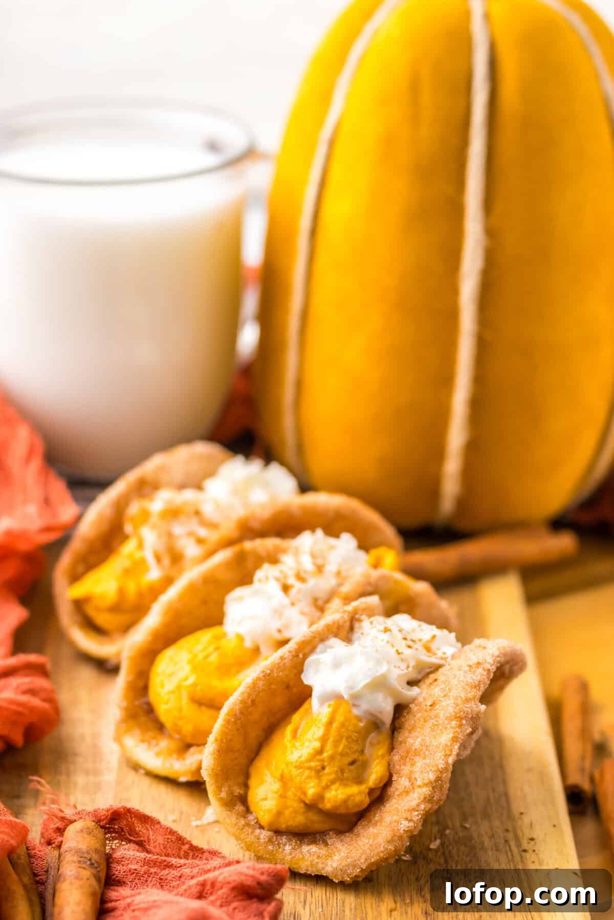 Three small tacos filled with creamy pumpkin pie filling and topped with whipped cream