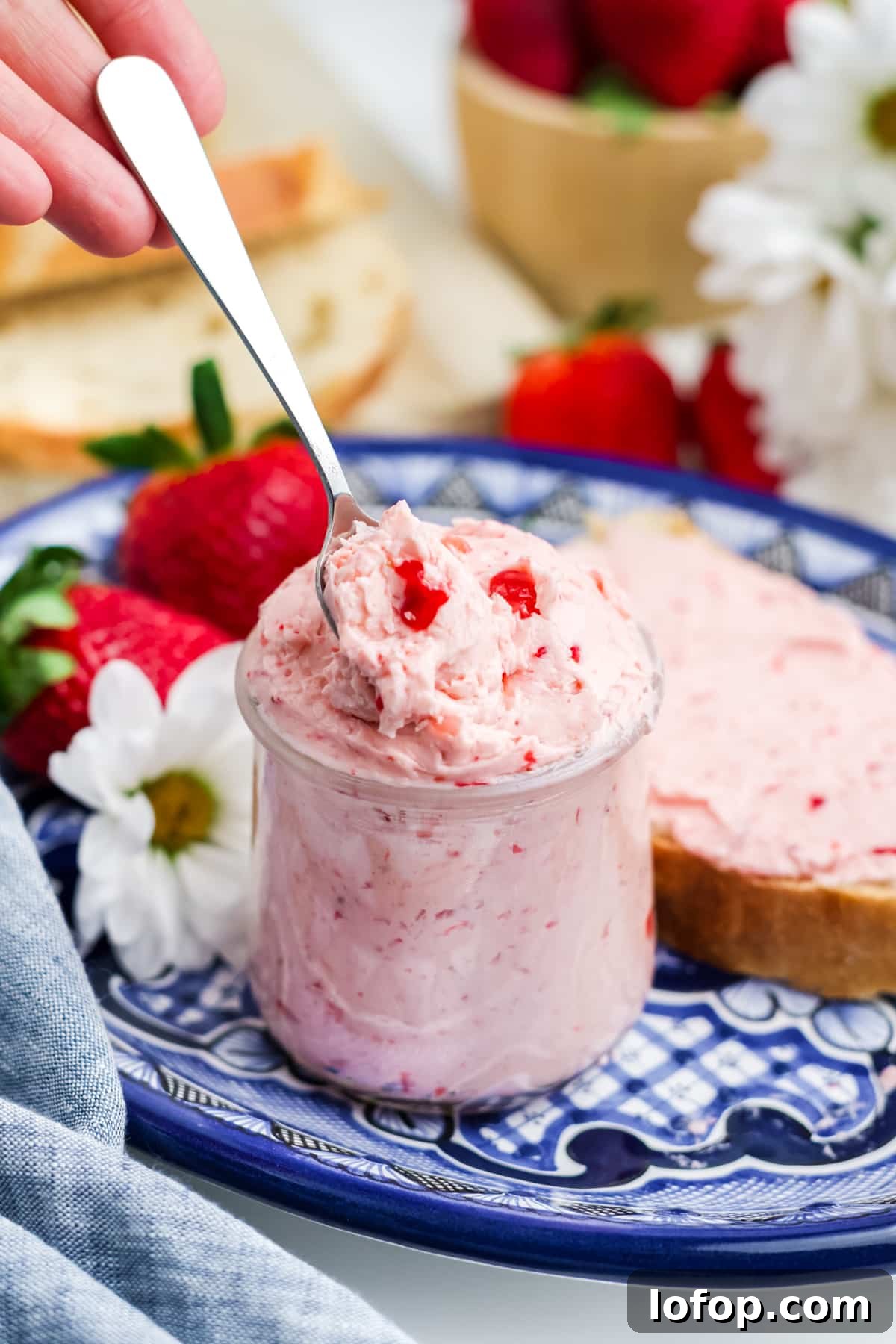 Homemade Strawberry Butter Recipe: Sweet Spread for Toasts and Baked Goods 2 Strawberry butter in a jar on a white and blue plate.