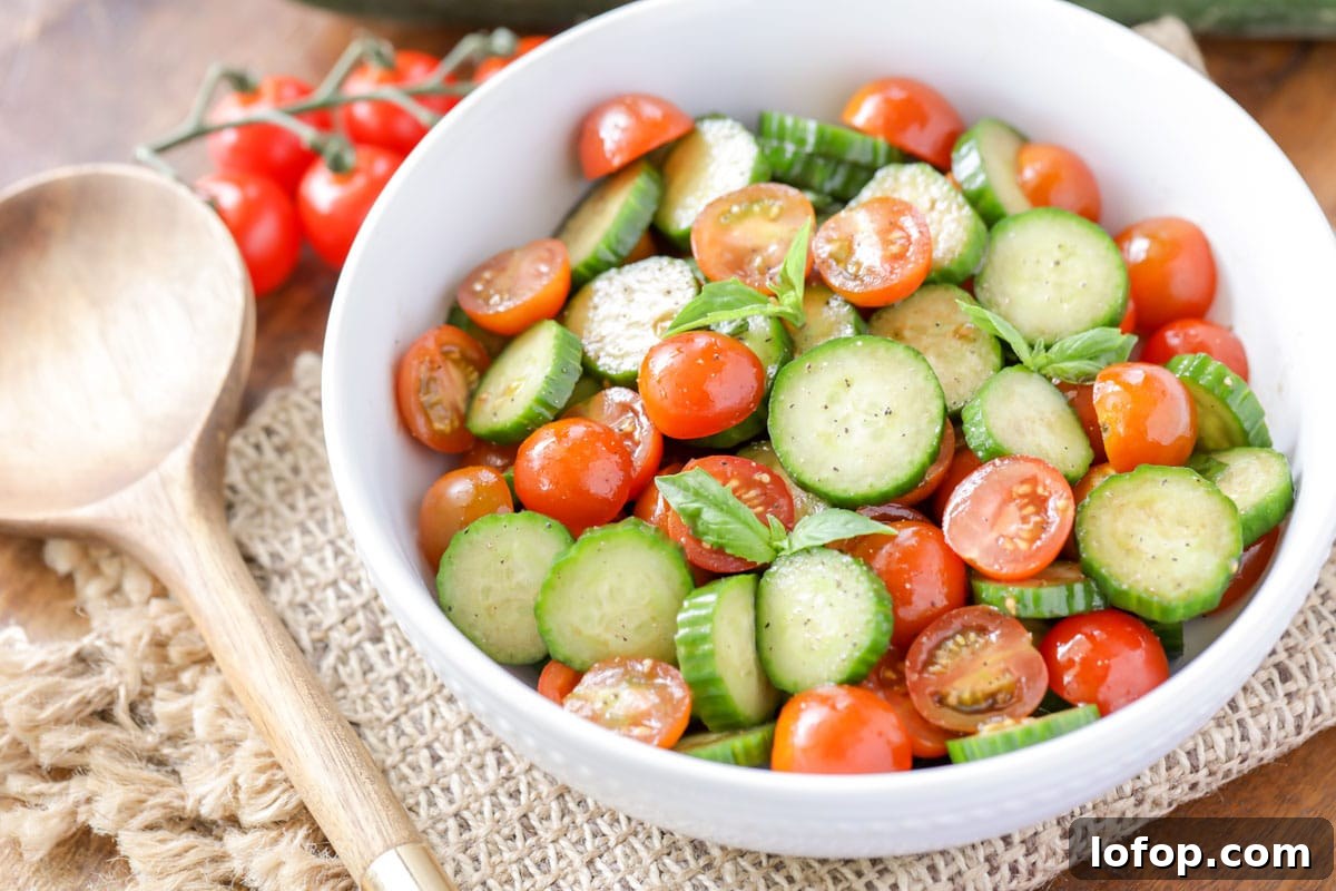 Fresh, vibrant Cucumber Tomato Salad is a simple salad perfect for summer and your bounteous harvest. It's a quick side for any meal! White bowl filled with Cucumber Tomato Salad.