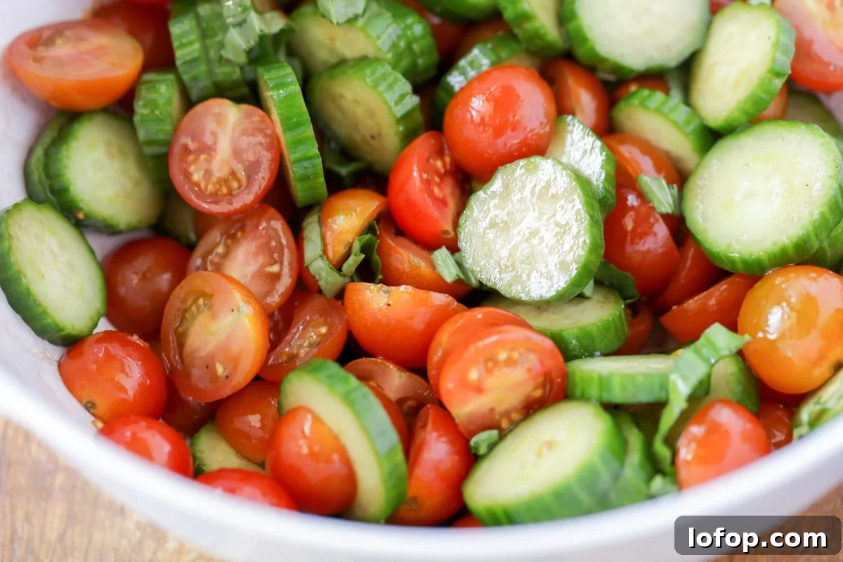 Fresh, vibrant Cucumber Tomato Salad is a simple salad perfect for summer and your bounteous harvest. It's a quick side for any meal! Fresh Cucumber Tomato Salad lightly dressed in a white bowl.