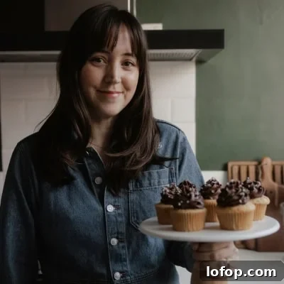 Decadent Chocolate Cupcakes with Cream Cheese Frosting 16 Ella from Alpine Ella is holding a cake stand with cupcakes on it.